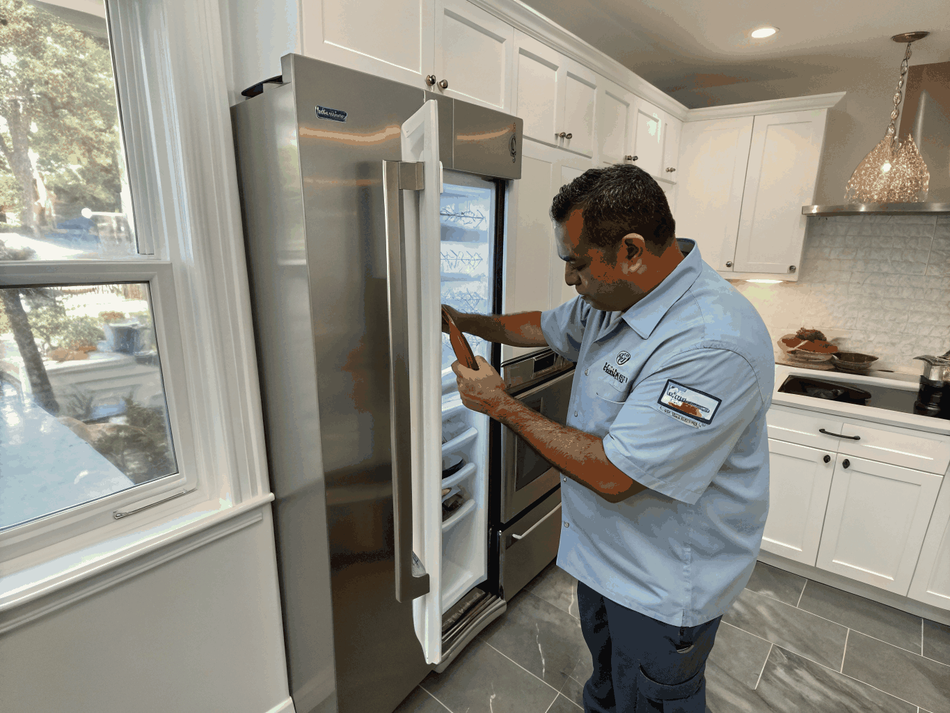 Technician servicing a modern GE refrigerator